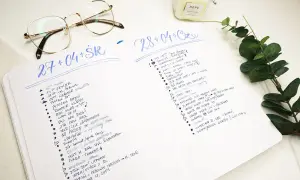 Bullet journal pomysły na każdy dzień. Lista zadań i notatek w dzienniku, obok okulary i świeca.