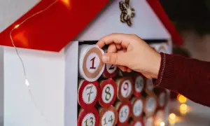Dziecko wkłada cyfrę "1" do domku, który jest kalendarzem adwentowym. To inspiracja, jak zrobic kalendarz adwentowy.