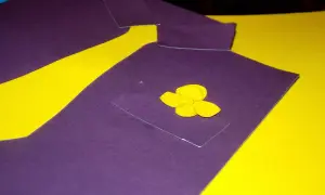 Fioletowa laurka na Dzień Taty w kształcie koszuli z żółtym kwiatkiem w kieszeni.