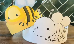 Dwie papierowe opaski pszczółki, jedna kolorowa, druga do pokolorowania, gotowe na przyjęcie.