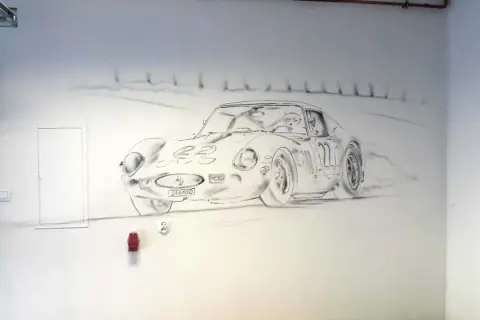 Rysunek na ścianie przedstawia klasyczny samochód sportowy, jak narysować motor w stylu retro.
