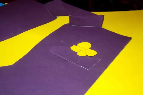Fioletowa laurka na Dzień Taty w kształcie koszuli z żółtym kwiatkiem w kieszeni.