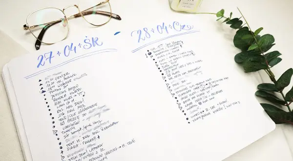 Bullet journal pomysły na każdy dzień. Lista zadań i notatek w dzienniku, obok okulary i świeca.