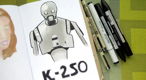 Rysunki markerami przedstawiają robota K-2SO i fragment twarzy. Obok leżą różnorodne pisaki.