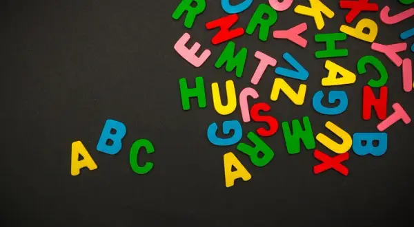 Kolorowe literki, jak czcionki na Facebooka, tworzą na czarnym tle alfabet. W lewym dolnym rogu widnieje napis "ABC".
