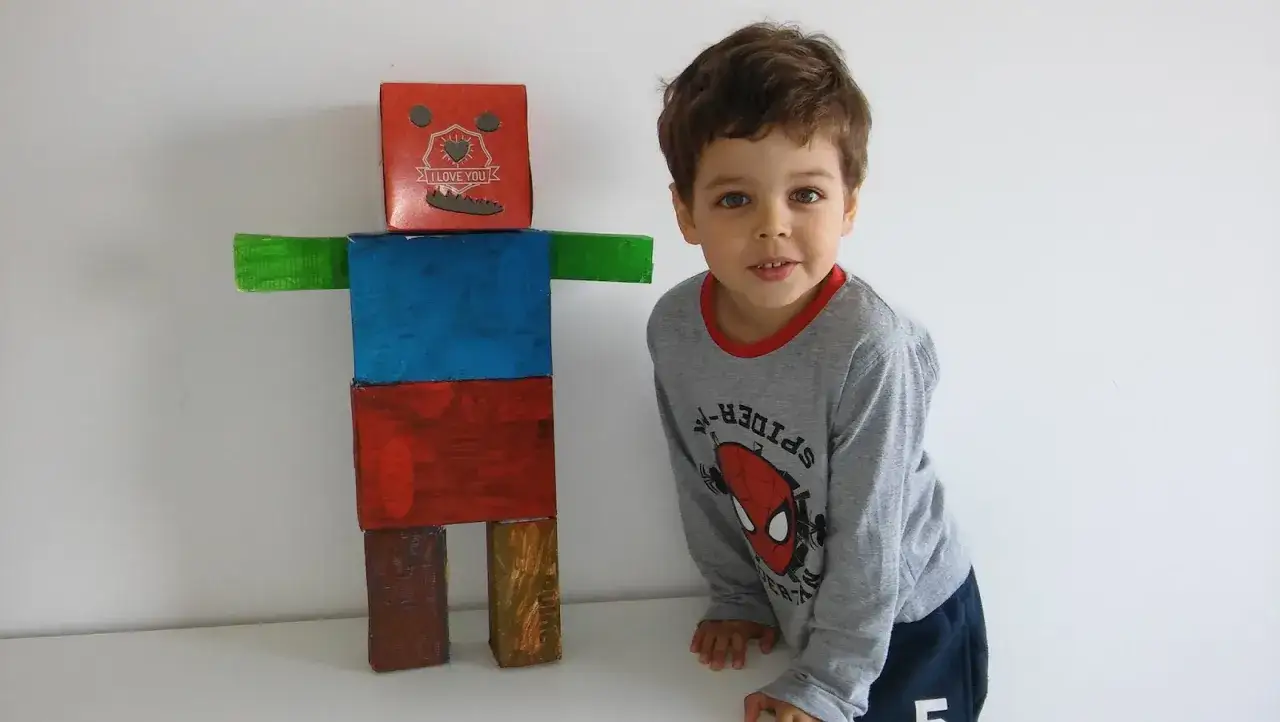 Chłopiec z dumą prezentuje swojego robota z recyklingu. Zobacz, jak zrobić robota z recyklingu, inspirując się tym kolorowym dziełem!
