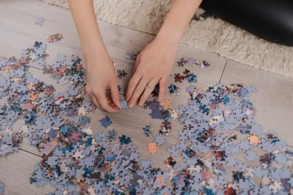 Ręce układają fragmenty obrazka, tworząc własne dzieło sztuki. To relaksujące puzzle DIY.